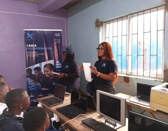 Sandra teaching students in a classroom beside an I Am A Changemaker banner
